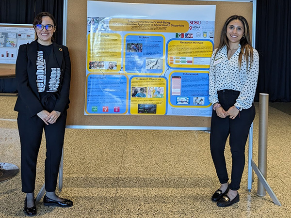 female faculty and female student stand in front of poster presentation